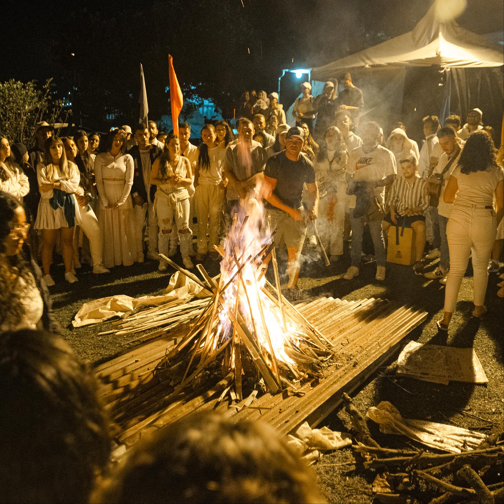Jóvenes reunidos alrededor de una fogata por la noche